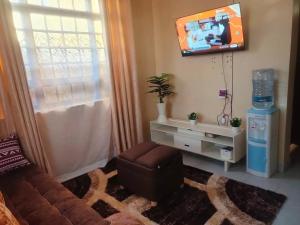 a living room with a couch and a tv on the wall at Murangiri Accommodations Mahnoor in Mombasa