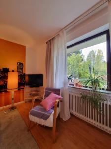 a living room with a chair and a large window at Gemütliche Ferienwohnung mit Blick ins Grüne in Wadern