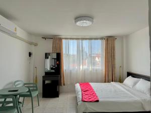 a bedroom with a bed and a table and a window at Baan Kalaya Homestay in Nonthaburi