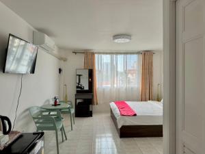 a bedroom with a bed and a table and a television at Baan Kalaya Homestay in Nonthaburi