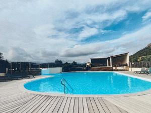 a large blue swimming pool on a wooden deck at Mini villa proche plage Santa Giulia in Porto-Vecchio