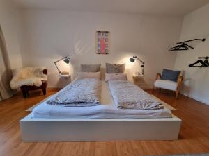 a white bed in a room with two chairs at Gemütliche Ferienwohnung mit Blick ins Grüne in Wadern