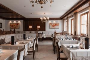 ein Restaurant mit weißen Tischen und Stühlen und einem Kronleuchter in der Unterkunft Hotel Waldhof in Percha