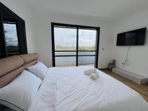 a bedroom with a large white bed with a flat screen tv at Villa Sol Aviv - וילה מושלמת עם בריכה פרטית למשפחות וקבוצות בנתיבות in Netivot +13 photos