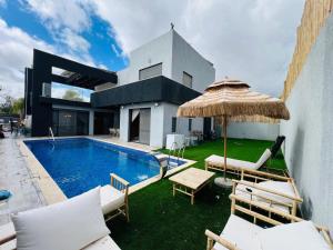 a villa with a swimming pool with chairs and an umbrella at Villa Sol Aviv - וילה מושלמת עם בריכה פרטית למשפחות וקבוצות בנתיבות in Netivot