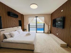 a bedroom with a white bed and a television at Villa Sol Aviv - וילה מושלמת עם בריכה פרטית למשפחות וקבוצות בנתיבות in Netivot
