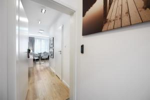 einen Flur, der zu einem Wohnzimmer mit einem Gemälde an der Wand führt in der Unterkunft Kalia Apartments in Warschau
