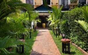a brick path in front of a house with palm trees at Central Indochine d'Angkor Hotel in Siem Reap +114 photos