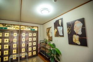 a hallway with a door and some pictures on the wall at TIDA house urasoe in Urazoe
