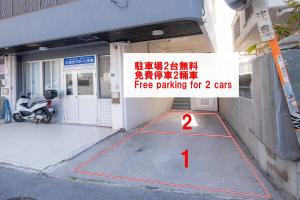 a parking lot with a sign on the side of a building at TIDA house urasoe in Urazoe