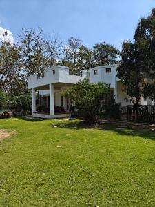 a white house with a lawn in front of it at Chandrakanta farm stay in Lucknow