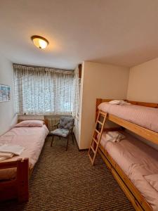 a bedroom with two bunk beds and a chair at Pragma Apartments - Cupido's Alpine Nest in Bellamonte