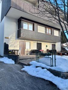 a house with a balcony and a table in the snow at Pragma Apartments - Cupido's Alpine Nest in Bellamonte