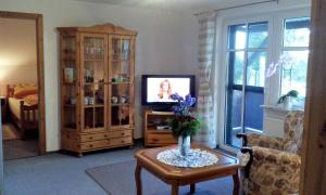 a living room with a tv and a table with flowers at Ferienwohnung Sievers in Barlt