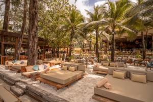 an outdoor patio with couches and tables and palm trees at Café del Mar Phuket - Suite & Penthouse in Kamala Beach