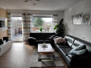 a living room with a black leather couch and a table at Ferienwohnung Lorke in Thiersheim