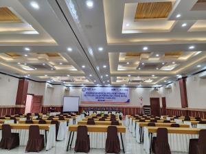 a conference hall with tables and chairs and a screen at hotel diana in Banda Aceh +4 photos