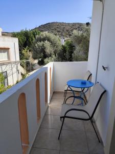 a small balcony with a blue table and chairs at Vangelis rooms in Pitsidia