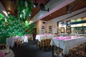 un restaurante con mesas y sillas blancas y una pared verde en Manly Hotel en Brisbane