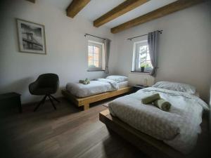 a bedroom with two beds and a chair and two windows at Chalupa na Kopci in Liberec