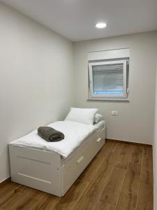 a white bedroom with a bed and a window at Apartman Lea in Sibinj