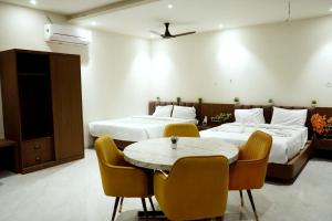 a hotel room with two beds and a table and chairs at Hotel Leena Inn in Jhālāwār