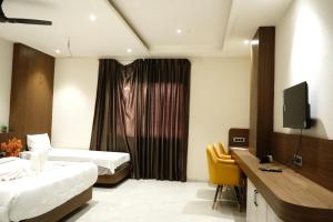 a hotel room with two beds and a television at Hotel Leena Inn in Jhālāwār
