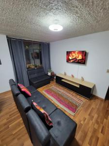 a living room with a black couch and a flat screen tv at Llama House Cusco in Cusco +8 photos