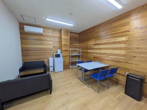 a room with wooden walls and a table and chairs at hostel 丹鶴 in Shingū