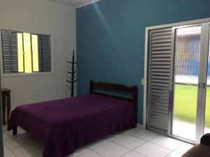 a bedroom with a purple bed and a window at Casa Praia Boracéia Bertioga in Boracéia