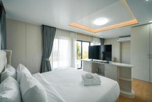 a hotel room with a white bed and a television at Olympus khaoyai in Ban Nong Makha +30 photos