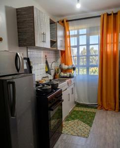 a kitchen with an orange curtain and a stove at Esidai Sidai in Narok