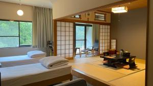 a room with two beds and a desk in a room at 霧島花紫 in Kirishima