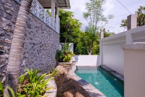 a house with a swimming pool and a stone wall at Bukit Adi in Amed