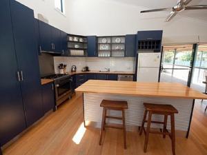 a kitchen with blue cabinets and a wooden table and stools at Cambroe in Lakes Entrance