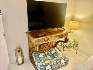 a tv sitting on top of a wooden entertainment center at Footsteps to Freshwater Beach in Freshwater