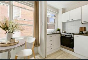 a kitchen with white cabinets and a table with chairs at Footsteps to Freshwater Beach in Freshwater