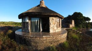 a small brick building with a window in a field at DaisyRiver Cottage in Port Alfred