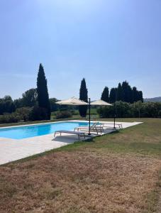 a swimming pool with two benches and umbrellas at Tenuta La Macina in Polpenazze del Garda