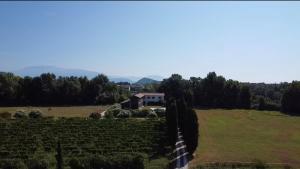 a farm in a field with a house in the distance at Tenuta La Macina in Polpenazze del Garda