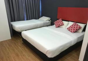 two beds with red and white pillows in a room at The Red Hotel in Bandar Saujana Putra