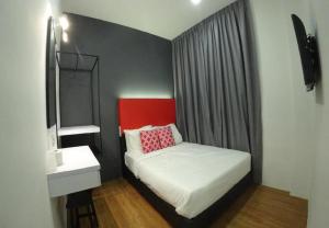 a small bedroom with a bed and a mirror at The Red Hotel in Bandar Saujana Putra