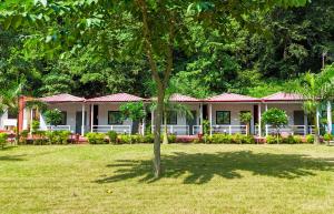 a row of houses with a tree in the yard at Ekantam Riverside Resort in Bijni