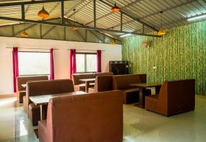 a waiting room with chairs and tables and green walls at Ekantam Riverside Resort in Bijni