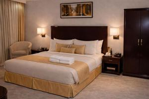 a hotel room with a large bed and a chair at Carawan Al Khaleej Hotel Olaya in Riyadh