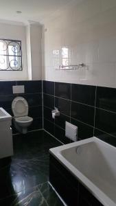 a black and white bathroom with a tub and a toilet at MB California Guest House in Bonabéri