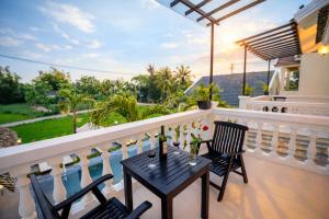 a balcony with two chairs and a table with drinks on it at The Son Villa Hội An in Danang +36 photos