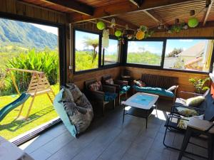 a screened in porch with couches and a swing at le ti coin papi hugues in La Plaine des Palmistes