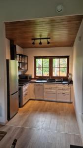 a large kitchen with white appliances and wooden ceilings at Domek na Cyplu Ostrowskim in Ostrowo +10 photos