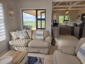 a living room with a couch and a kitchen at Elephant View Homestead - Hydrangea Cottage in Plettenberg Bay